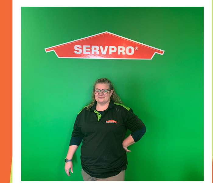 Photo of woman, Chrissy, wearing glasses standing in front of a SERVPRO logo